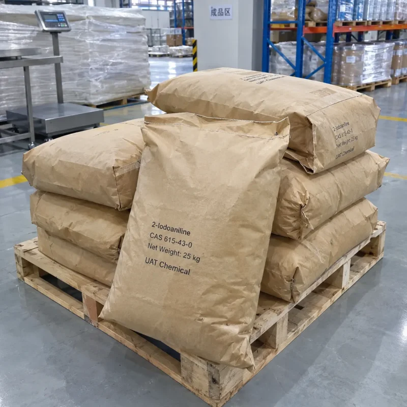 2-iodoaniline-cas-615-43-0-25kg-paper-bags-pallet Stacked 25kg brown paper bags of 2-Iodoaniline CAS 615-43-0 on a wooden pallet in a finished goods warehouse area with a platform scale behind.