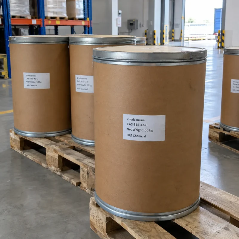 2-iodoaniline-cas-615-43-0-50kg-fiber-drums-pallet Brown fiber drums labeled 2-Iodoaniline CAS 615-43-0 with 50 kg net weight on wooden pallets in a warehouse with racks and a loading door in the background.