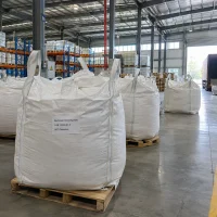 White FIBC bulk bags labeled Aluminum Chlorohydrate CAS 12042-91-0 on wooden pallets in a warehouse with a container truck in the background.