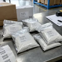 Silver foil bags of white Boron Nitride powder CAS 10043-11-5 with 1 kg net weight on a packing table next to labeled cartons and barcode labels.