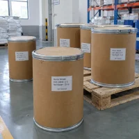 Several 25kg brown fiber drums of Boron Nitride CAS 10043-11-5 on a wooden pallet in a warehouse with racks and blue drums in the background.