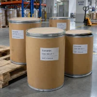 Several brown fiber drums of Curcumin CAS 458-37-7 stacked on a wooden pallet in a chemical warehouse storage area.