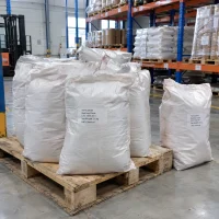 ferric-oxide-red-iron-oxide-cas-1309-37-1-25kg-woven-bags-pallet Stacked white 25kg bags of Ferric Oxide Red Iron Oxide CAS 1309-37-1 on a wooden pallet in a warehouse storage area.
