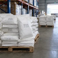 Maleic Acid (CAS 110-16-7) in white woven bags stacked on wooden pallets in a warehouse