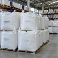 Stacked white FIBC bulk bags labeled Nitrilotriacetic Acid CAS 139-13-9 on wooden pallets in a warehouse with storage racks behind.