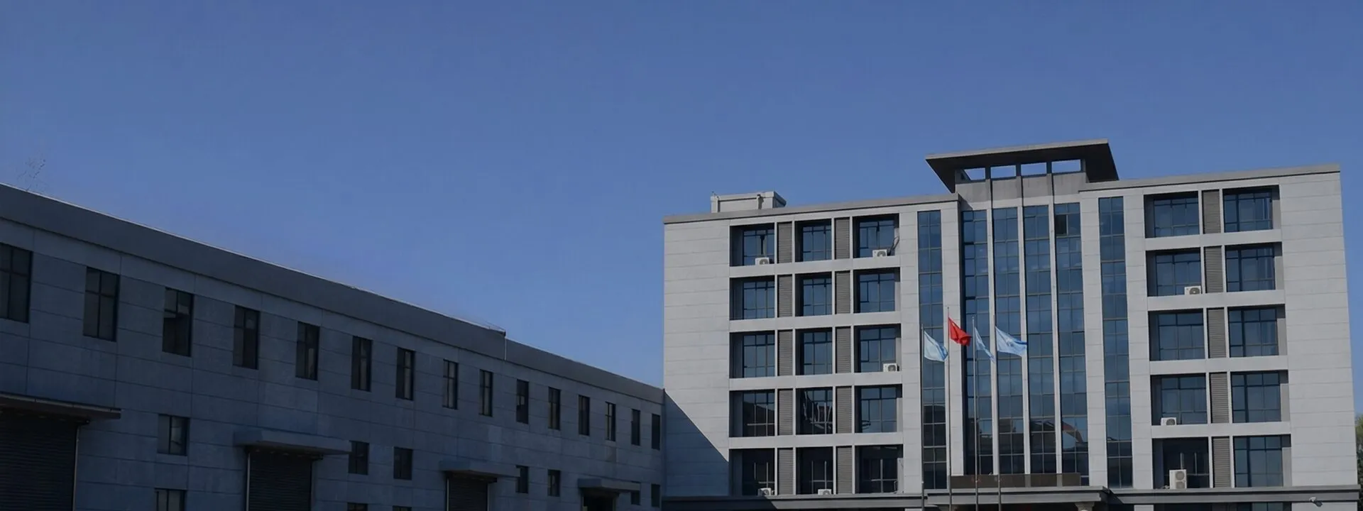 UATChem plant panorama: loading-bay workshops and flag-topped office tower, serving industry since 2006