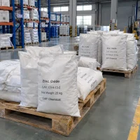 zinc-oxide-zno-cas-1314-13-2-25kg-woven-bags-pallet Stacked 25kg white woven bags of Zinc Oxide ZnO CAS 1314-13-2 on wooden pallets in a warehouse with racks, blue drums and a forklift in the background.